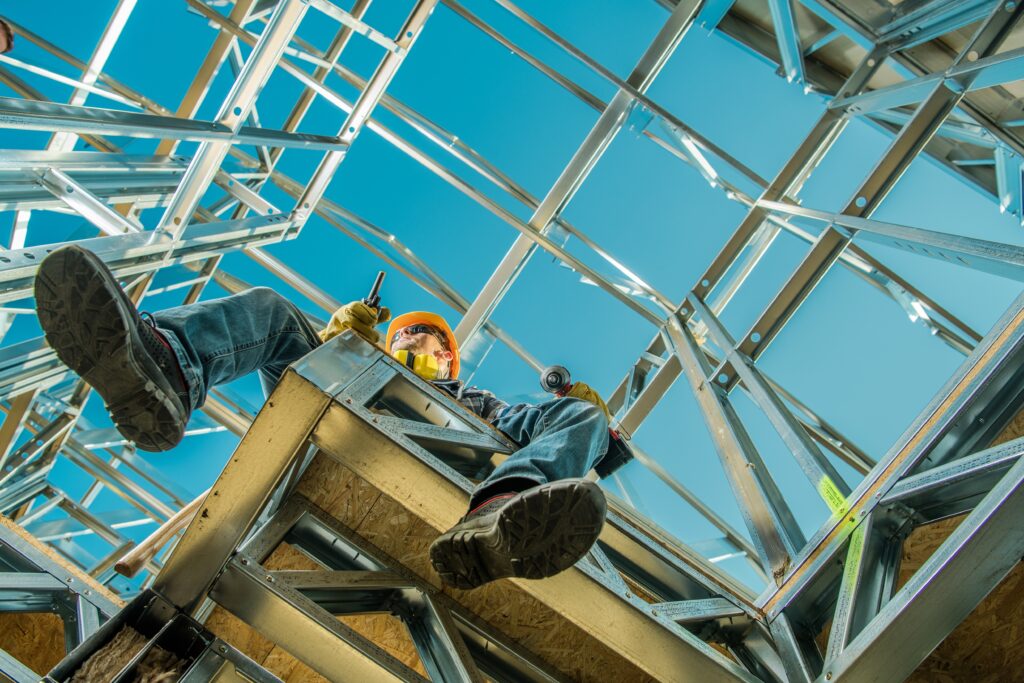 Industrial worker sitting on metal framework of building