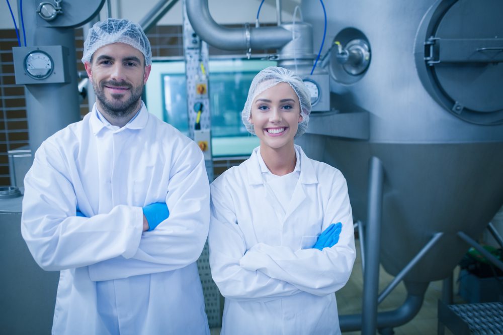 Man and woman in food processing plant standing in front of machines