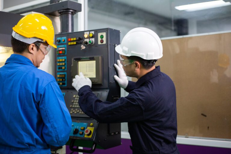Man explaining an industrial machine to a coworker in a workplace injury prevention exercise
