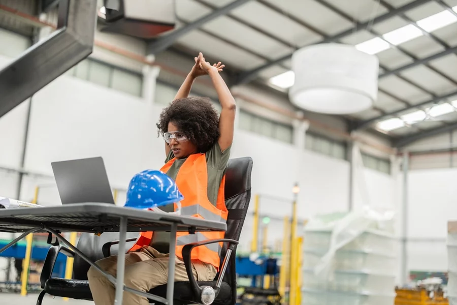 A woman stretching at a desk.