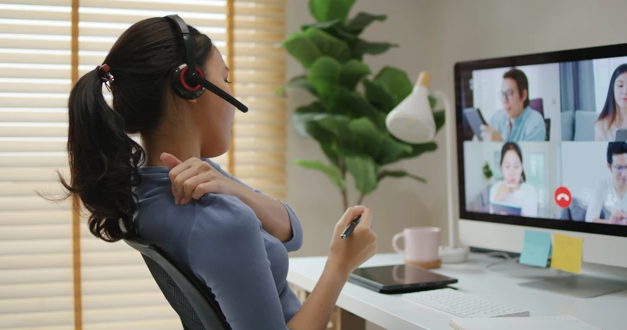 Woman with headset grabbing shoulder in pain