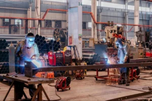 Factory workers in an industrial facility performing manufacturing tasks, relevant to pre-employment physical abilities testing (PAT) and workforce safety evaluation.