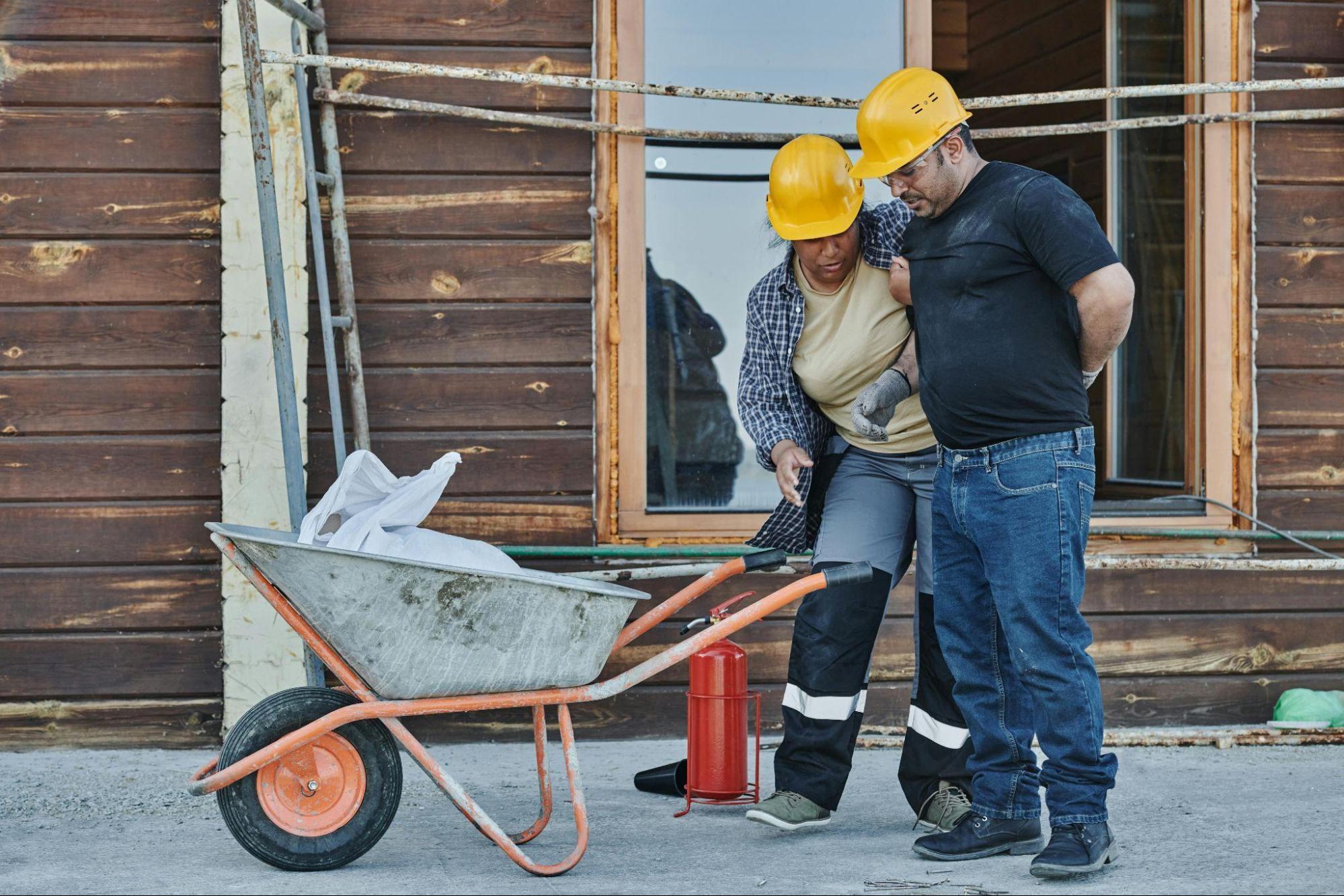 Construction workers assisting an injured employee, highlighting the importance of fitness for duty programs.