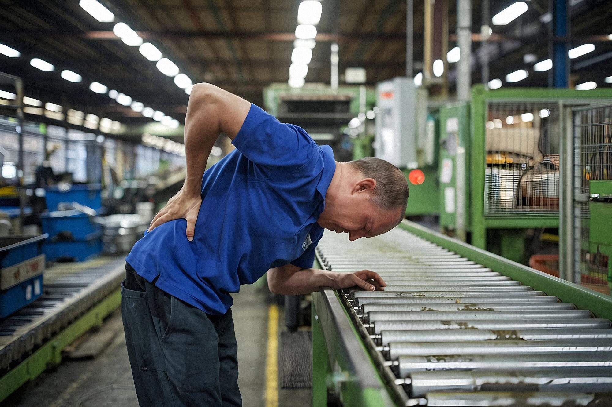 Warehouse employee experiencing lower back discomfort after manual material handling, illustrating the impact of work-related musculoskeletal disorders.